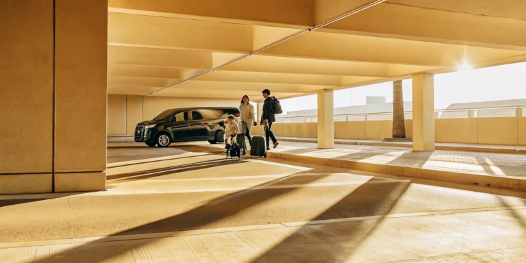 Private shuttle van at LAX airport terminal pickup curb with professional driver assisting family with luggage