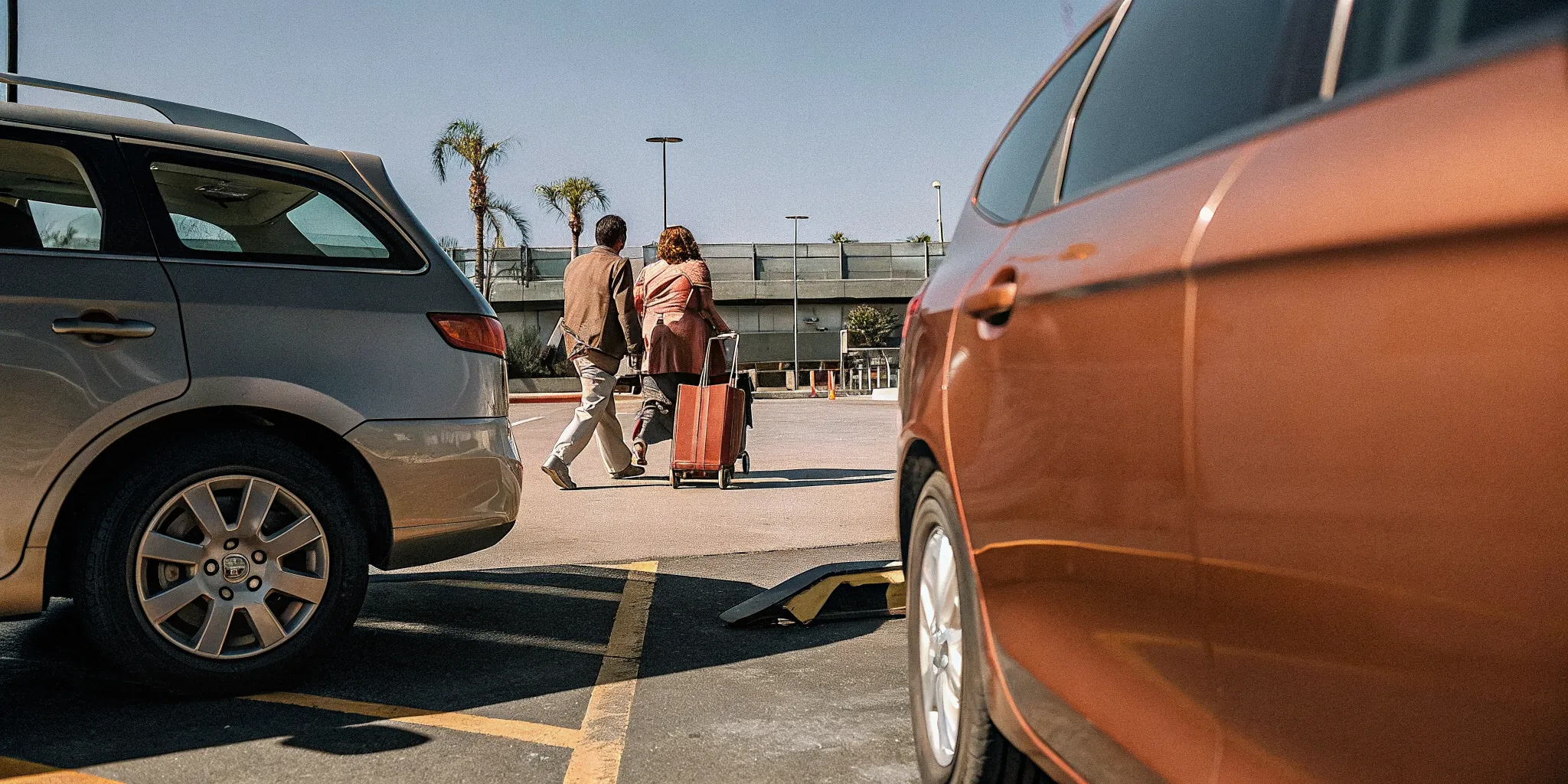 LAX airport terminal with a parked car in an economy lot and a private shuttle van, comparing parking vs shuttle travel options