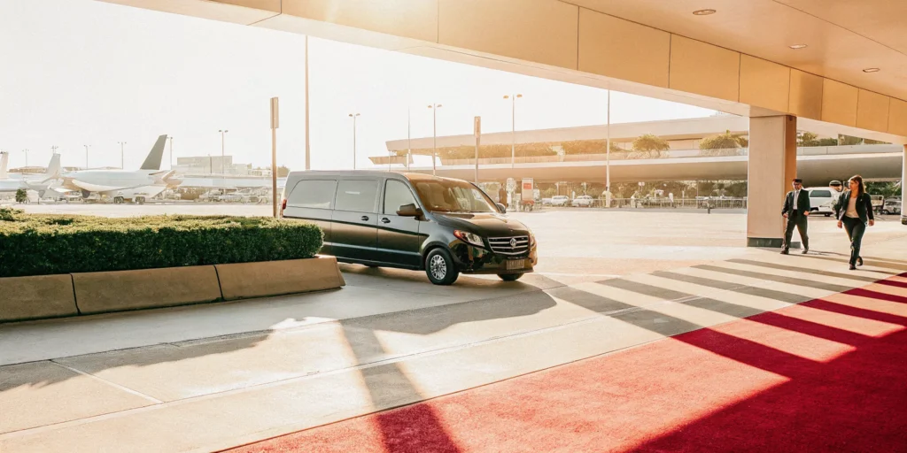 A professional premium private transport van driving past LAX airport terminal curbside