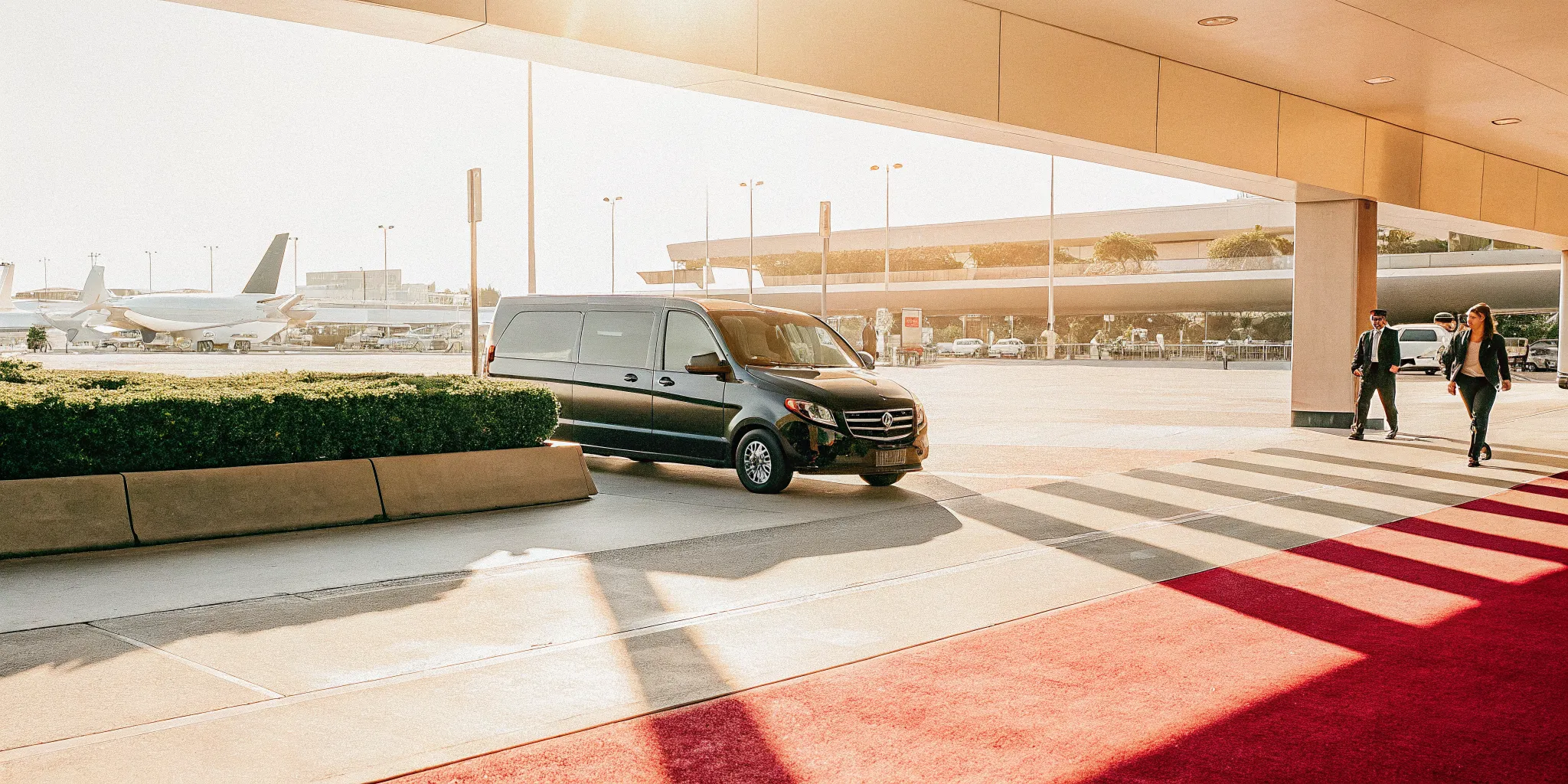 A professional premium private transport van driving past LAX airport terminal curbside