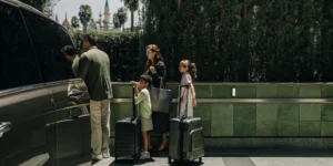 Family with luggage at LAX choosing between rental car counter and private shuttle van for Disneyland trip