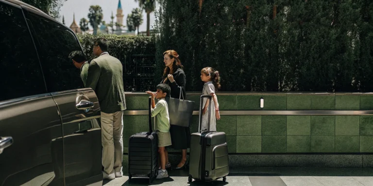 Family with luggage at LAX choosing between rental car counter and private shuttle van for Disneyland trip
