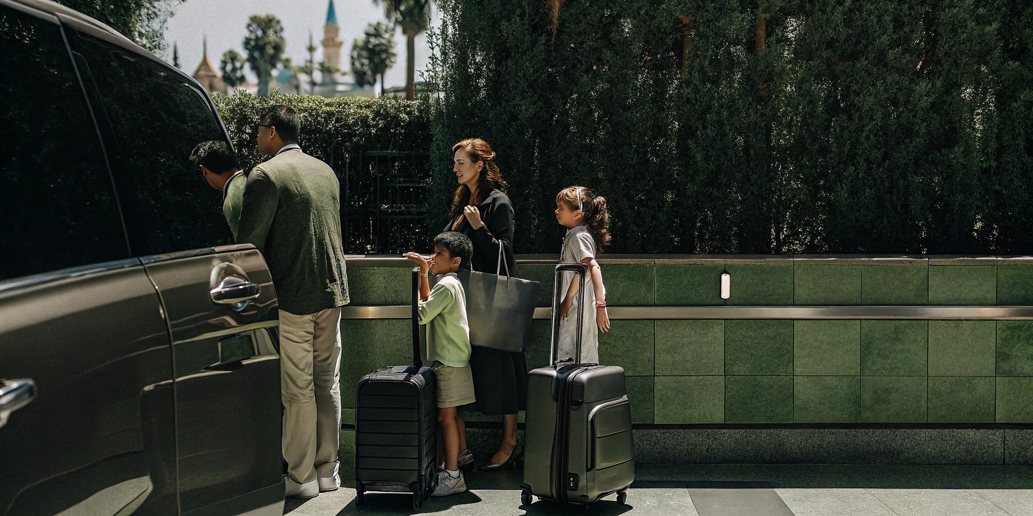 Family with luggage at LAX choosing between rental car counter and private shuttle van for Disneyland trip