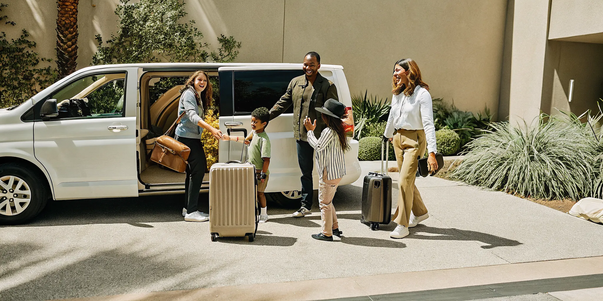 Large family with children and luggage boarding a private van at LAX airport for Disneyland trip