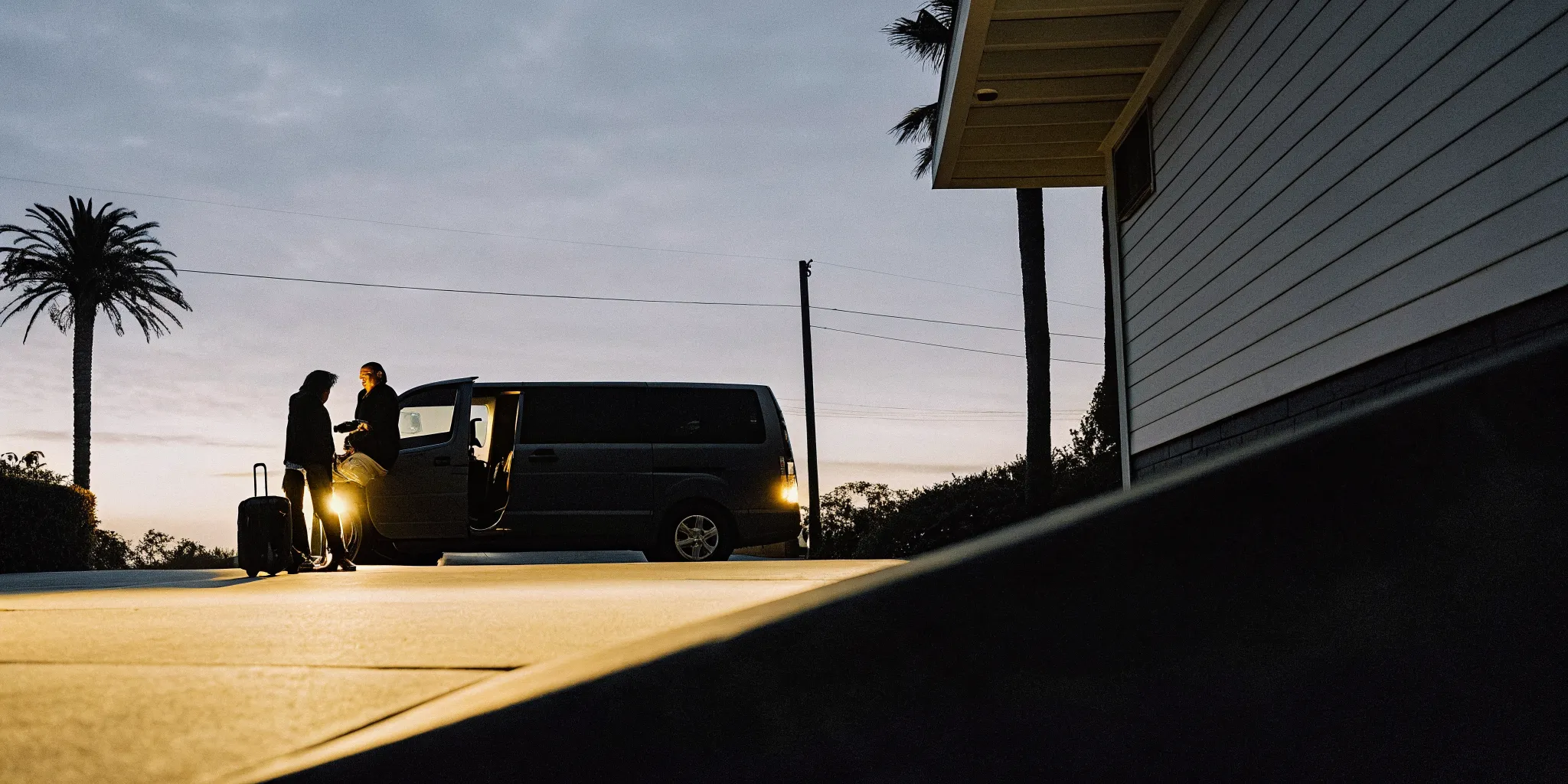 Private shuttle van picking up a traveler before dawn in Los Angeles for an early LAX flight